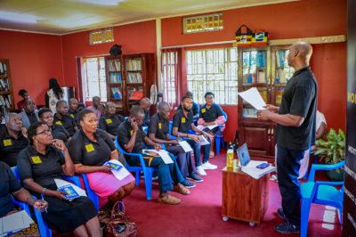 一间教室里坐满了穿着黑色polo衫的人，衫上有黄色的pepp - uganda标志. 